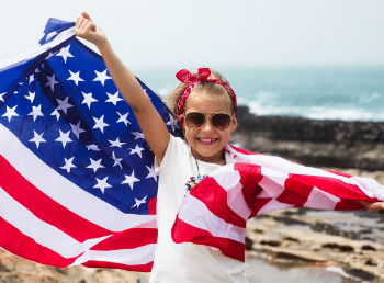 A girl holding an American flag on a beach