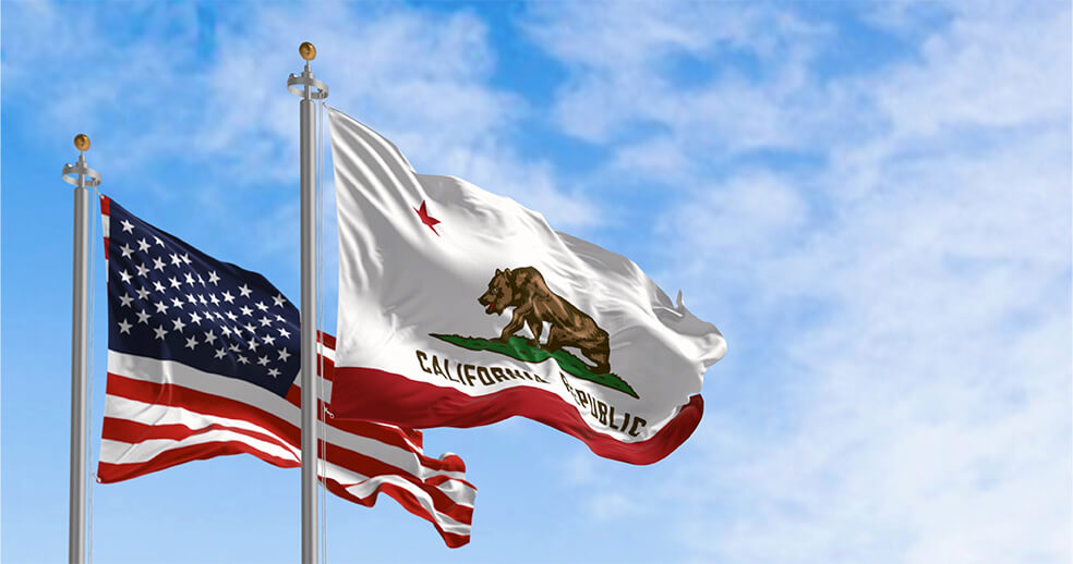 An American flag and a California flag blowing in the wind