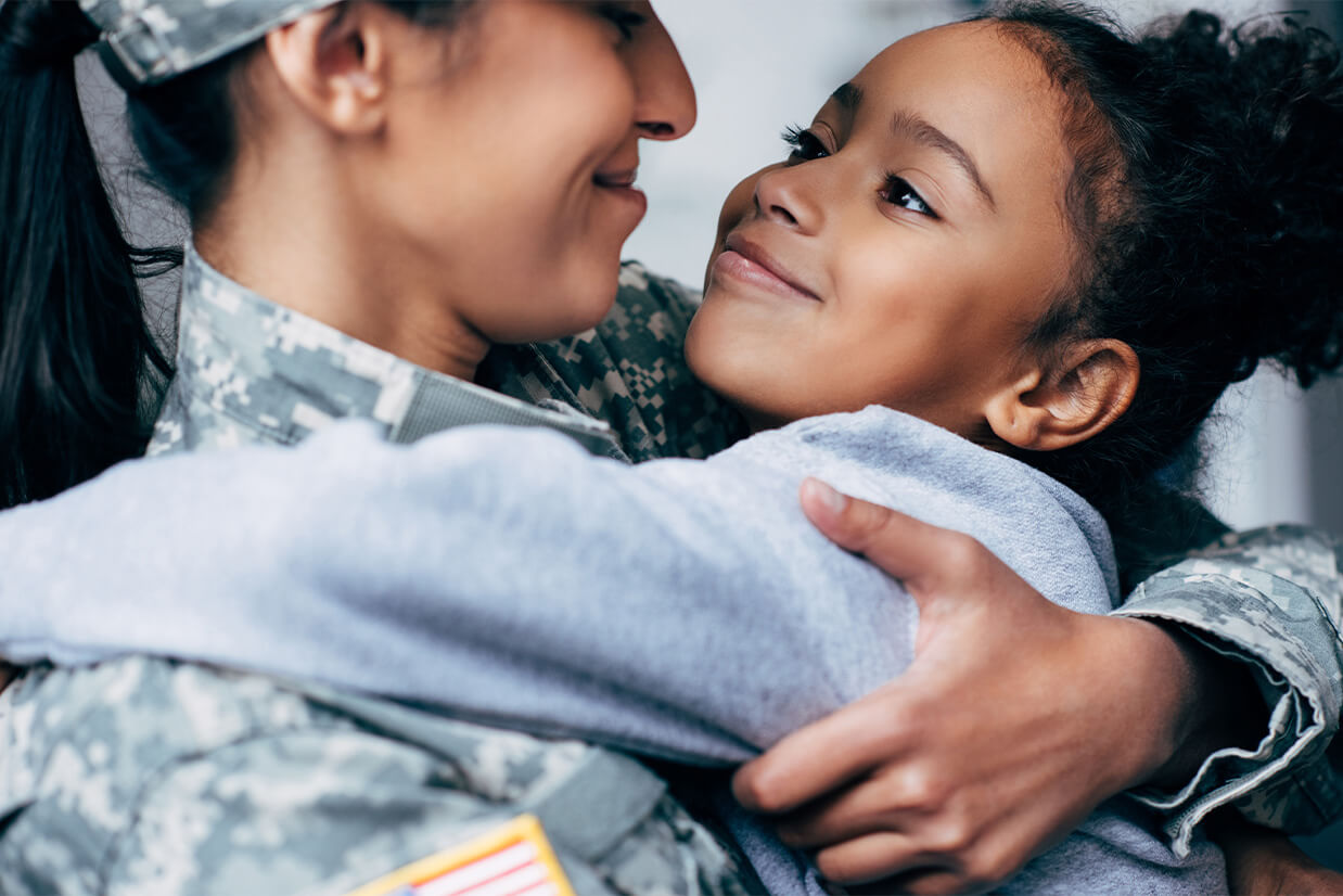 A female soldier in uniform holding her daughter